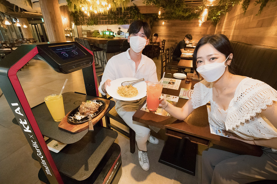 모델이 서울 강남구에 위치한 ‘매드포갈릭 봉은사 현대아이파크타워점’에서 KT AI 서빙로봇을 소개하고 있다. (사진=KT)