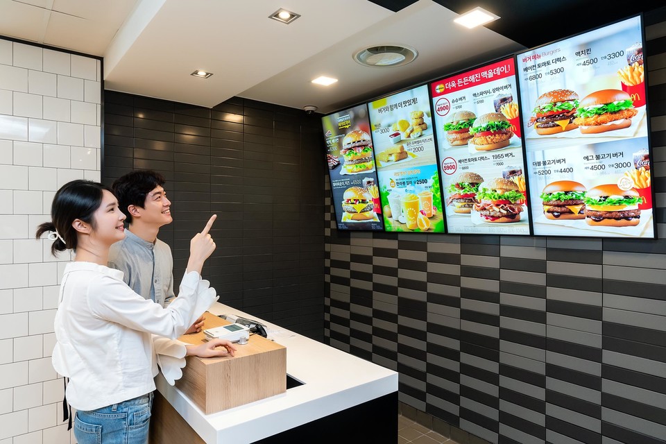삼성전자 모델이 경기도 고양시에 위치한 맥도날드 고양삼송DT점에 설치된 삼성 스마트 사이니지를 소개하고 있다. (사진=삼성전자)