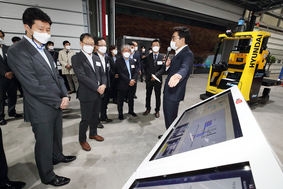 KT 구현모(왼쪽 두번째) 대표, 현대중공업지주 정기선(왼쪽 첫번째) 부사장 등 KT-현대중공업그룹 관계자들이 로봇물류시스템 데모센터에서 5G 기반 AI 무인지게차에 대한 설명을 듣고 있다. (사진=KT)