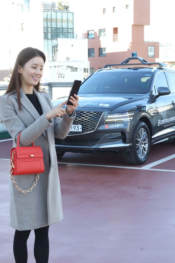 LG유플러스 모델이 서울시 상암 5G 자율주행 시범지구의 한 주차장에서 모바일 앱을 통해 5G 자율주행차 ‘A1(에이원)’의 주차를 완료시킨 모습 (사진=LG유플러스)