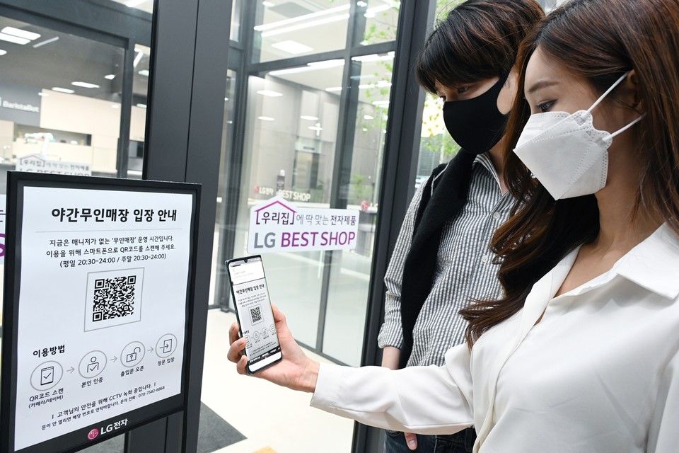 LG전자가 26일부터 국내 가전회사 가운데 처음으로 무인매장을 운영한다. 모델들이 매장에 들어가기 위해 입구에서 QR코드를 스캔해 본인 인증 절차를 진행하고 있다. (제공=LG전자)