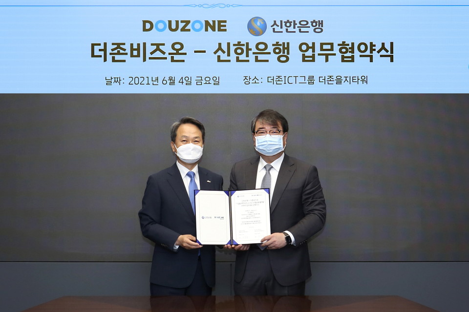 더존비즈온과 신한은행이 기업 디지털 금융 플랫폼 사업 공동 추진을 위한 업무제휴 양해각서를 체결한 가운데 왼쪽부터 신한은행 진옥동 은행장과 더존비즈온 김용우 대표가 협약서를 교환하고 있다. (제공=더존비즈온)