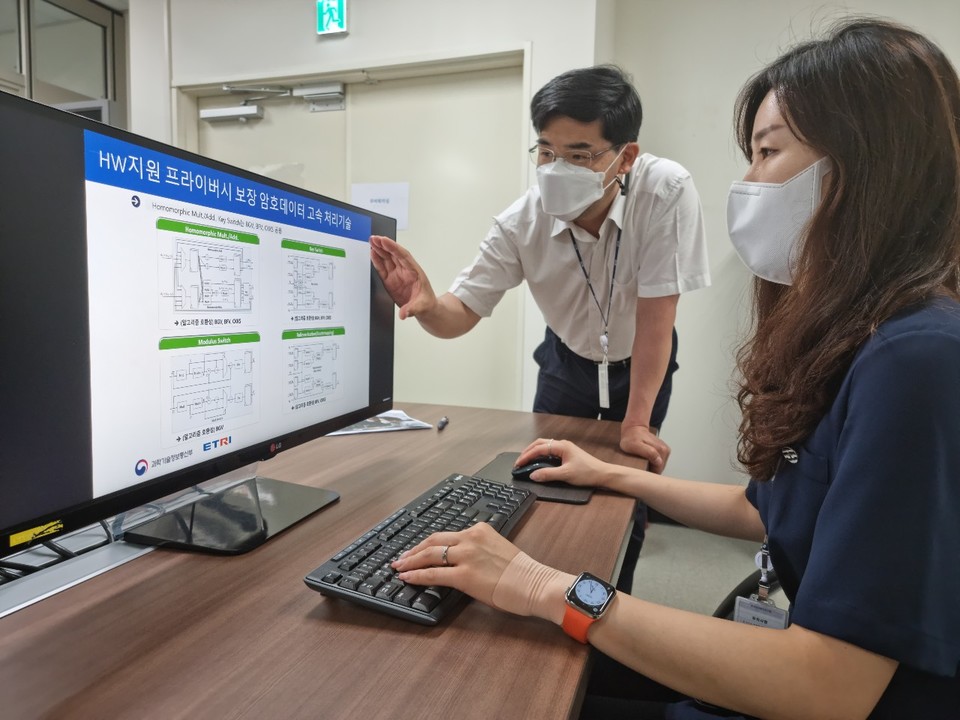 ETRI 연구진이 프라이버시 보장 암호데이터 고속처리기술의 개념도를 살펴보고 있다. (제공=ETRI)