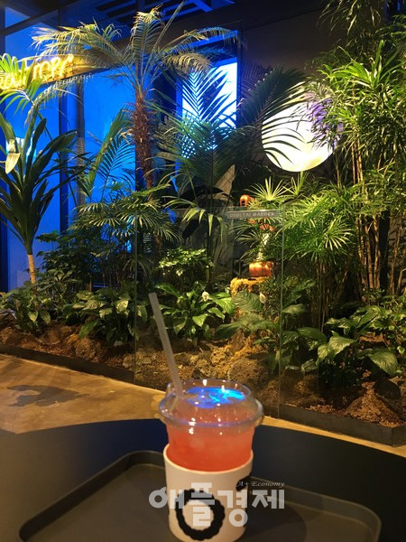 로봇이 제조한 음료. 맞은편 디지털 가든 안에는 플라밍고를 닮은 로봇이 있다.