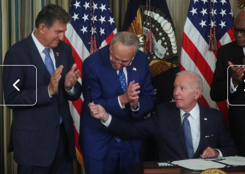 바이든 미 대통령이 '인플레이션 감축법'에 서명한 후 곁에 서있던 조 맨친 상원의원(왼쪽)에게 서명에 쓰인 만년필을 건네고 있다.(사진=로이터통신)