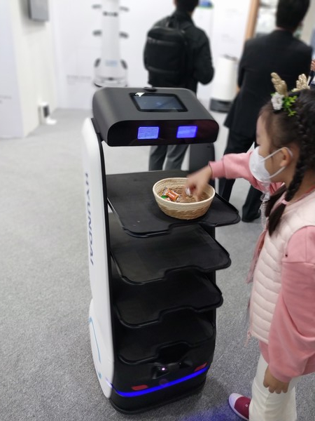 '2022 로보월드'에 출품된 서비스로봇에게서 한 어린이가 사탕을 집어들고 있다.