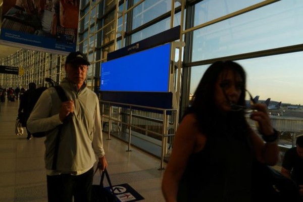 미국 뉴워크 공항의 BSOD화면의 안내 전광판앞을 탑승대기자들이 지나고 있다 . (사진=WSJ)