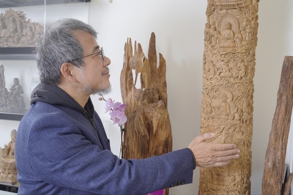  (섬세한 조각이 새겨진 침양목조 예술품을 어루만지는 가오스이(高世義), 그가 추진하는 침향문화와 전통 공예의 중요한 상징이자 옛 선인의 지혜에 대한 존경과 전승을 의미한다)